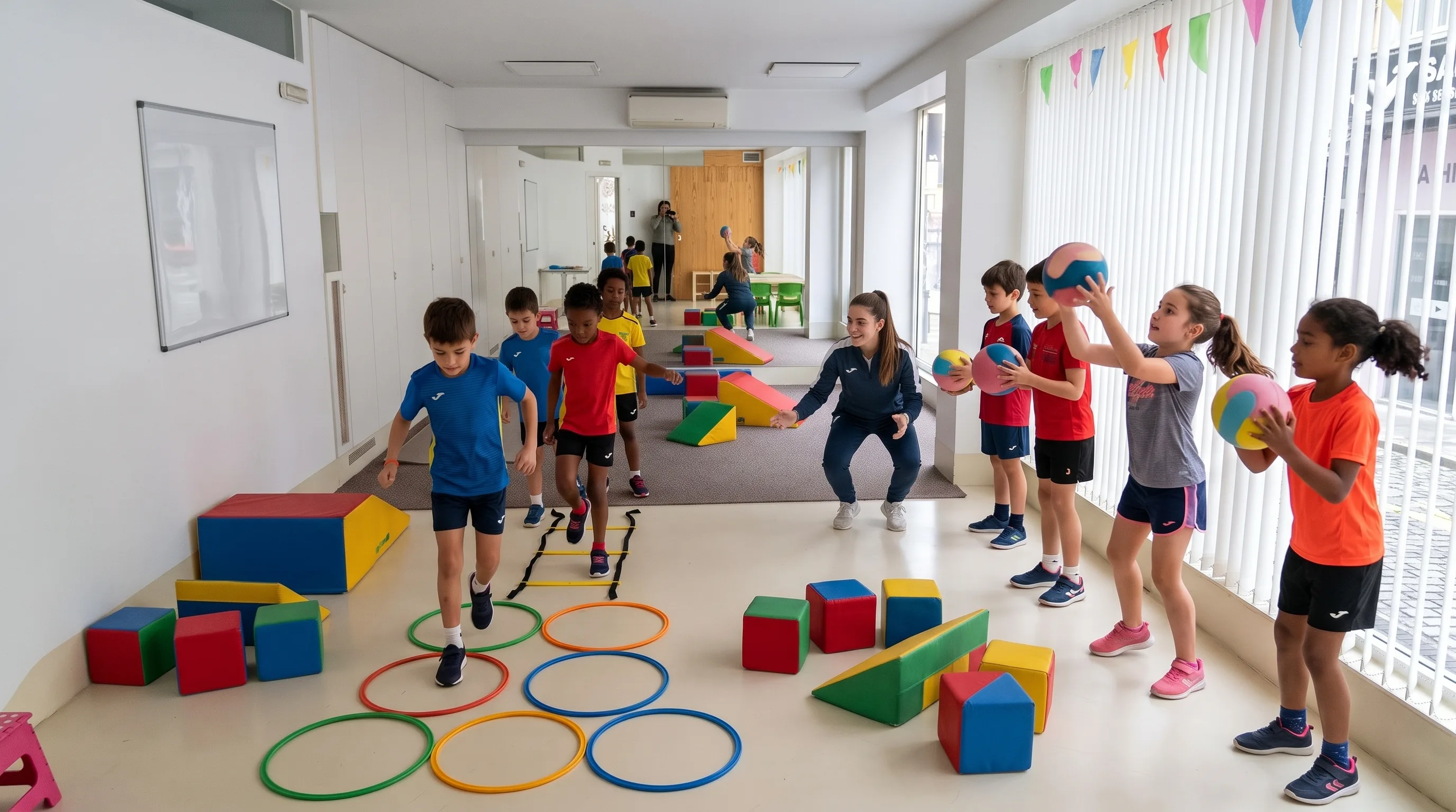 Niños entrenando fuerza y agilidad con balones medicinales, aros y bloques de espuma junto a su profesora en la sala de espejos de Move Lab