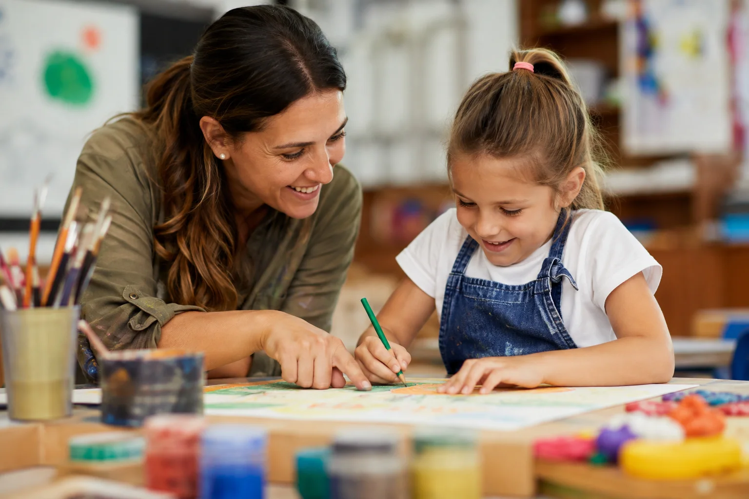 Niña dibujando con lápices de colores acompañada de su profesora durante Talent Lab
